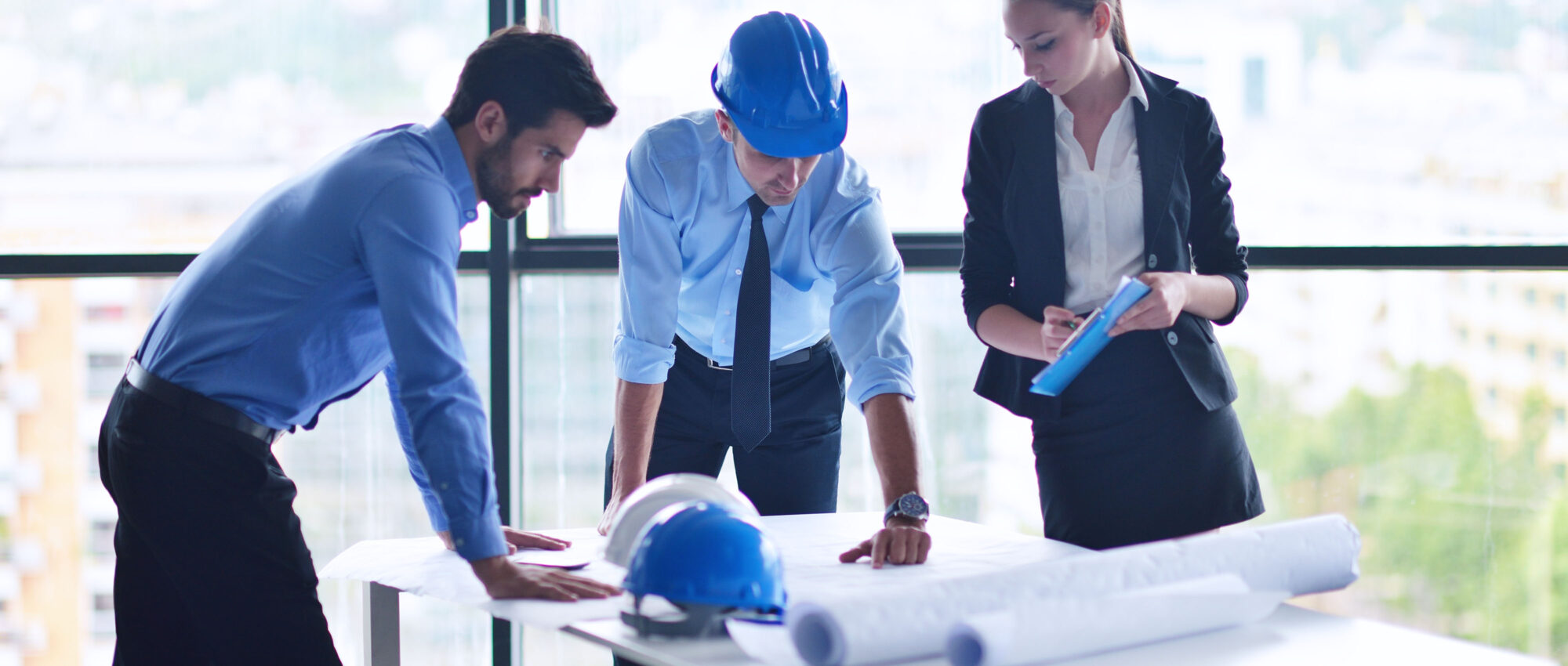 Project Management business people group on meeting and presentation in bright modern office with construction engineer architect and worker looking building model and blueprint planbleprint plans